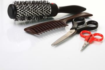 Beautician tools featuring hair brush, comb and scissors.
