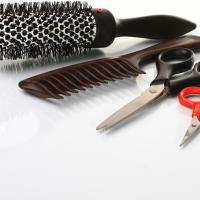 Beautician tools featuring hair brush, comb and scissors.